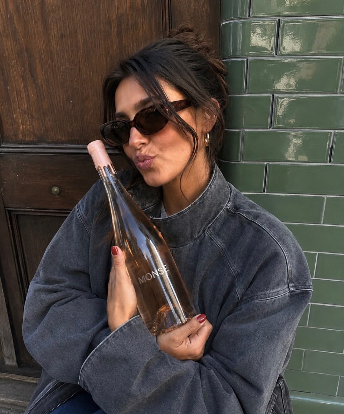 MONSE bottle held against a green tiled wall