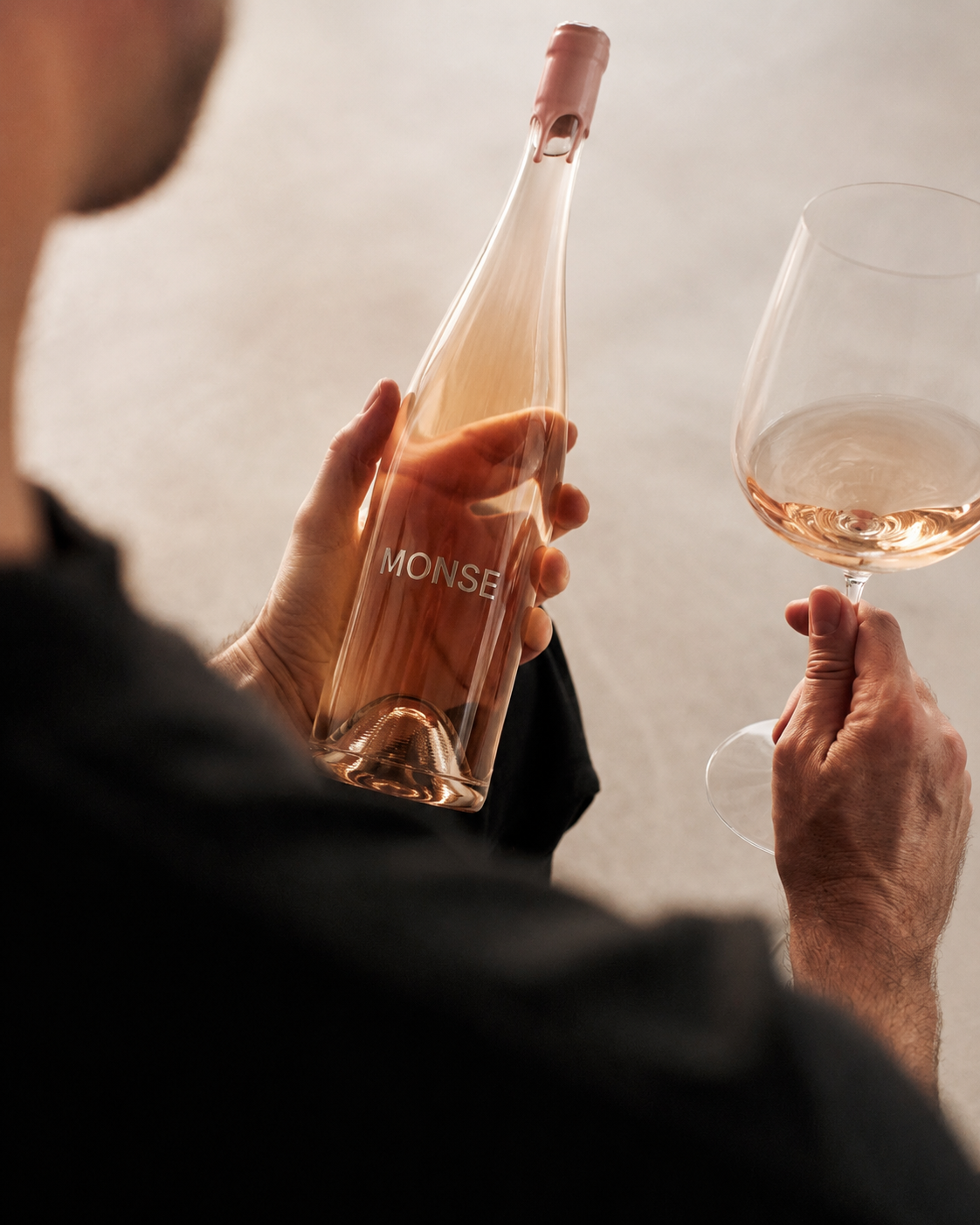 A man holding a MONSE rosé bottle and a poured glass in afternoon light